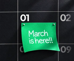 Illustrative green March reminder note on a dark calendar board.